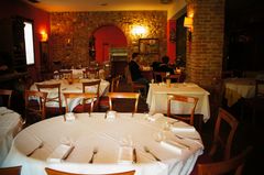 Sala di ristorante con pareti rosse e un tavolo rotondo apparecchiato con tovaglia bianca